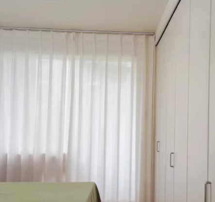 Hotel Curtain Tracks for Privacy and Light A stylish hotel room with a double curtain track system, showing a sheer curtain and a blackout curtain side-by-side.
