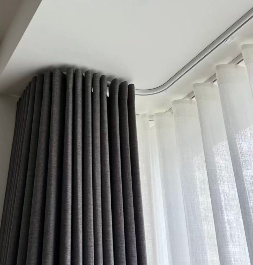 A perfectly installed curtain track following the curve of a large bay window in a hotel suite
