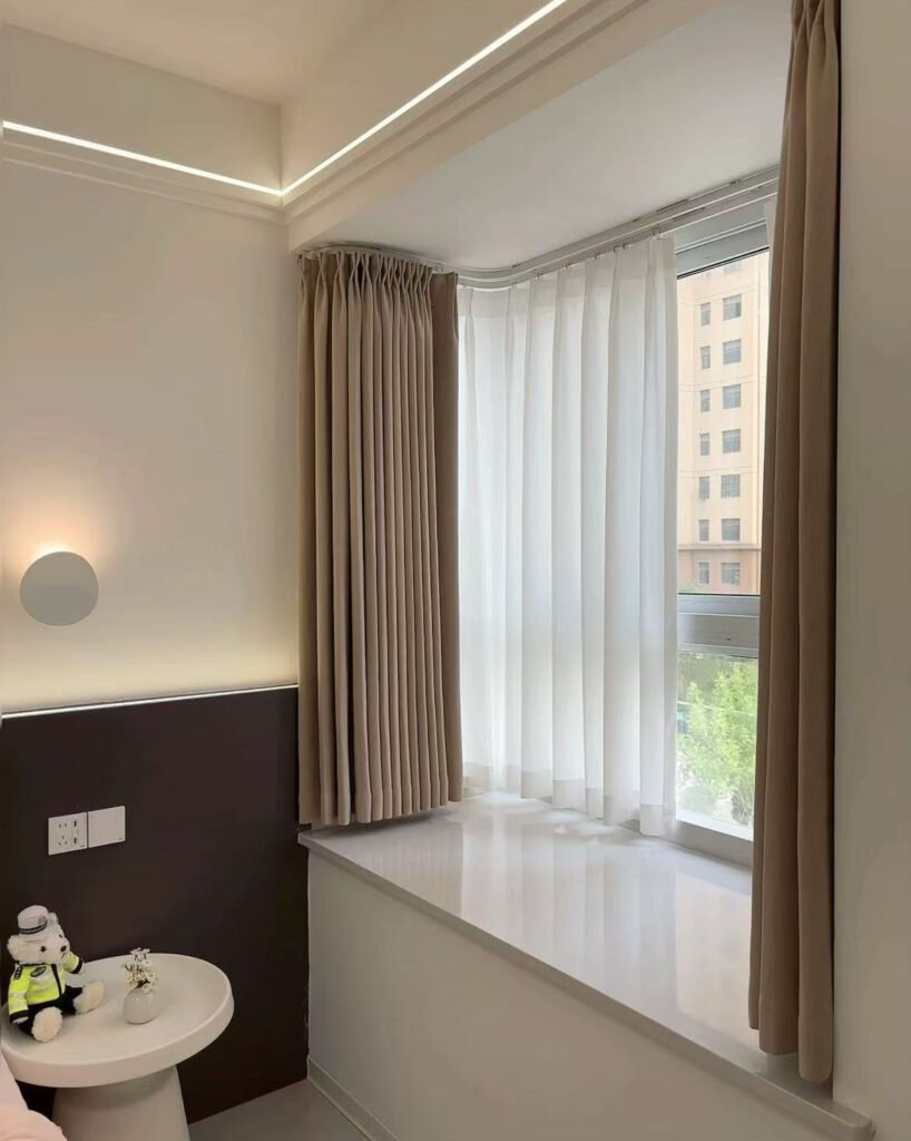 A smoothly curved curtain track used as a stylish room divider in a modern loft apartment