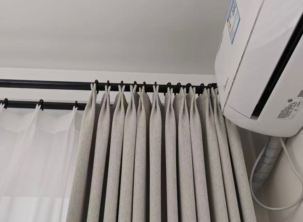 A window with a black frame and a matching black curtain track installed above it, against a light-colored wall.