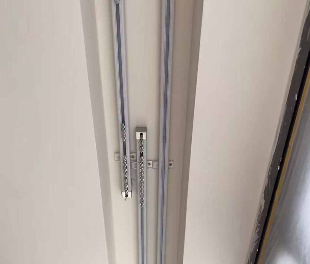 A heavy-duty commercial curtain track supporting thick blackout curtains in a theater