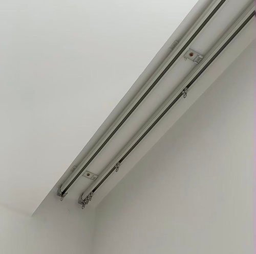 A custom-bent curtain track system navigating a curved bay window