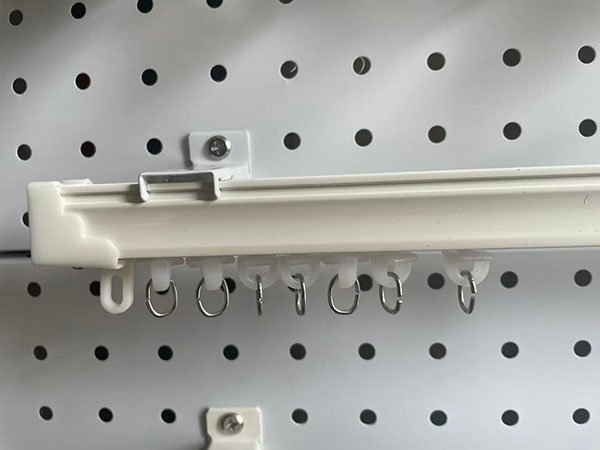 A purchasing manager inspecting curtain track samples in an office